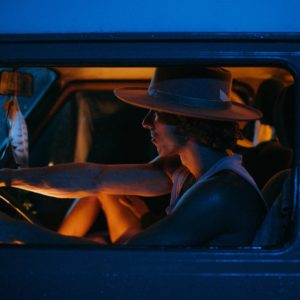man with a hat driving his car by night